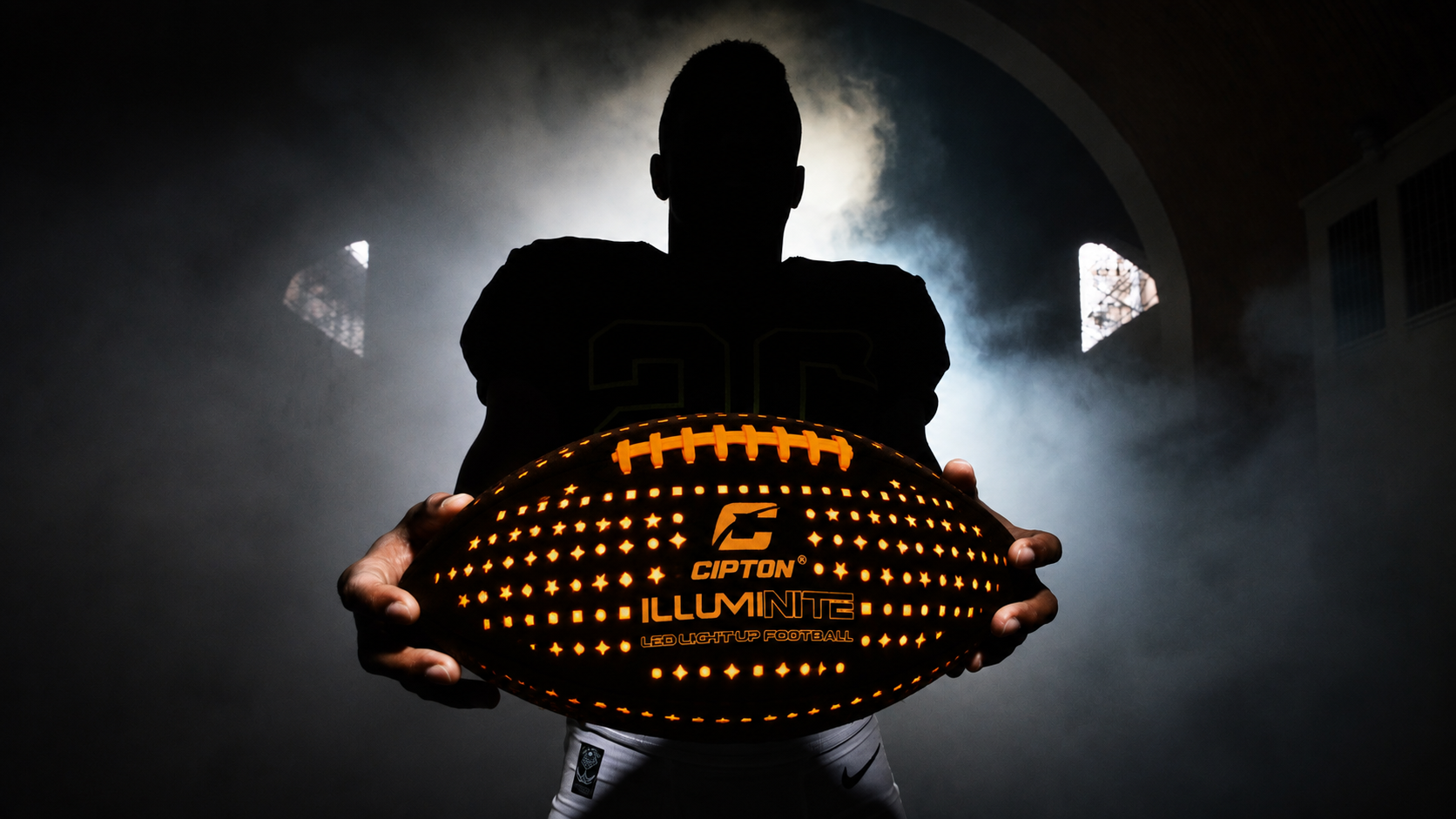 Player holding the glowing CIPTON LED football in a smoky tunnel