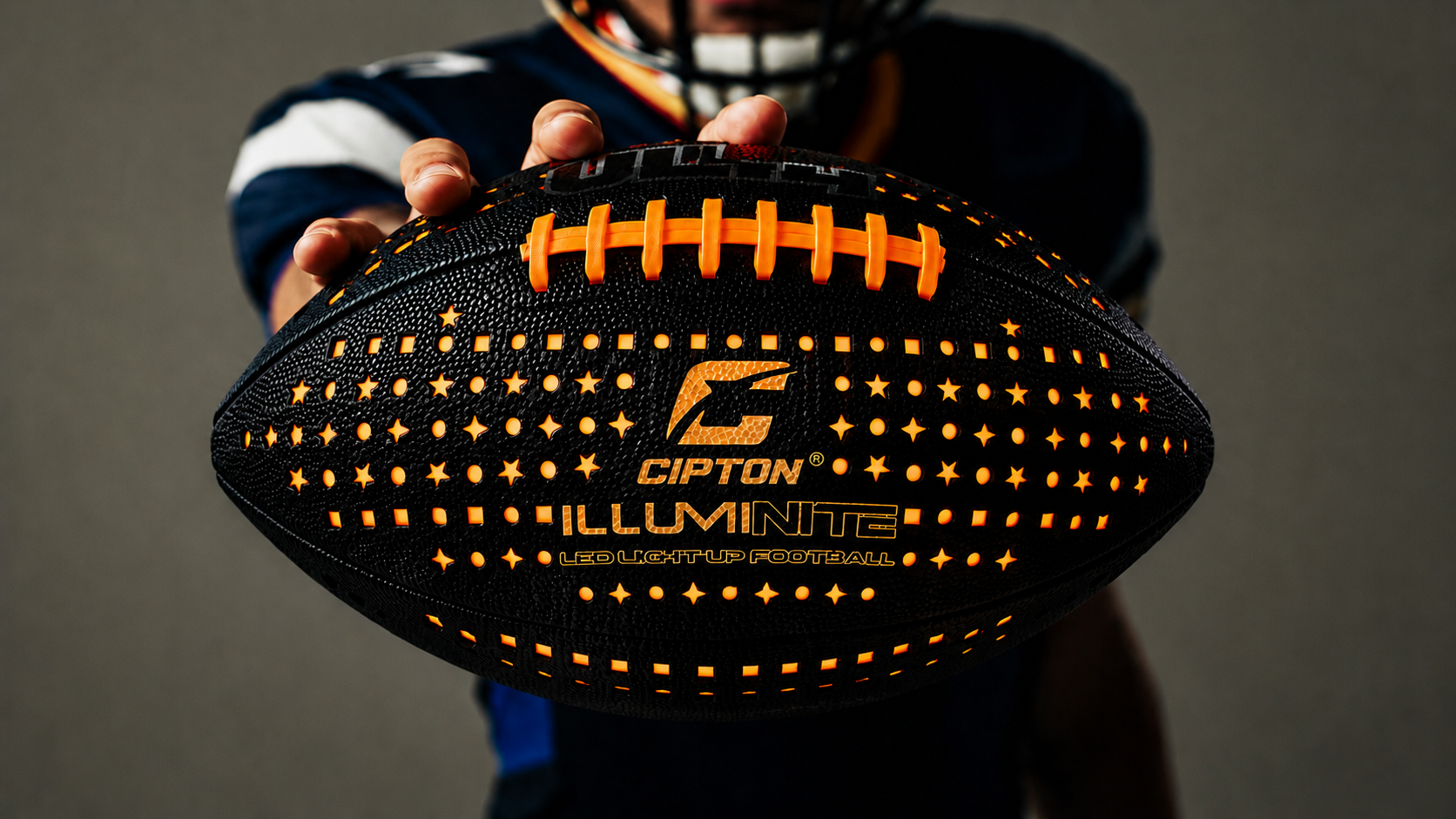 Player in a helmet holding out the glowing CIPTON LED football