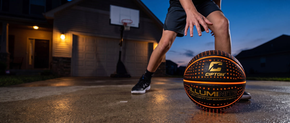 Cipton LED basketball mid-dribble on a driveway at dusk
