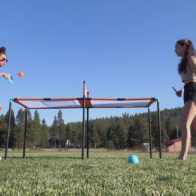 CIPTON Slam Pong Pro on a field, two players rallying over the center net with paddles, then hands